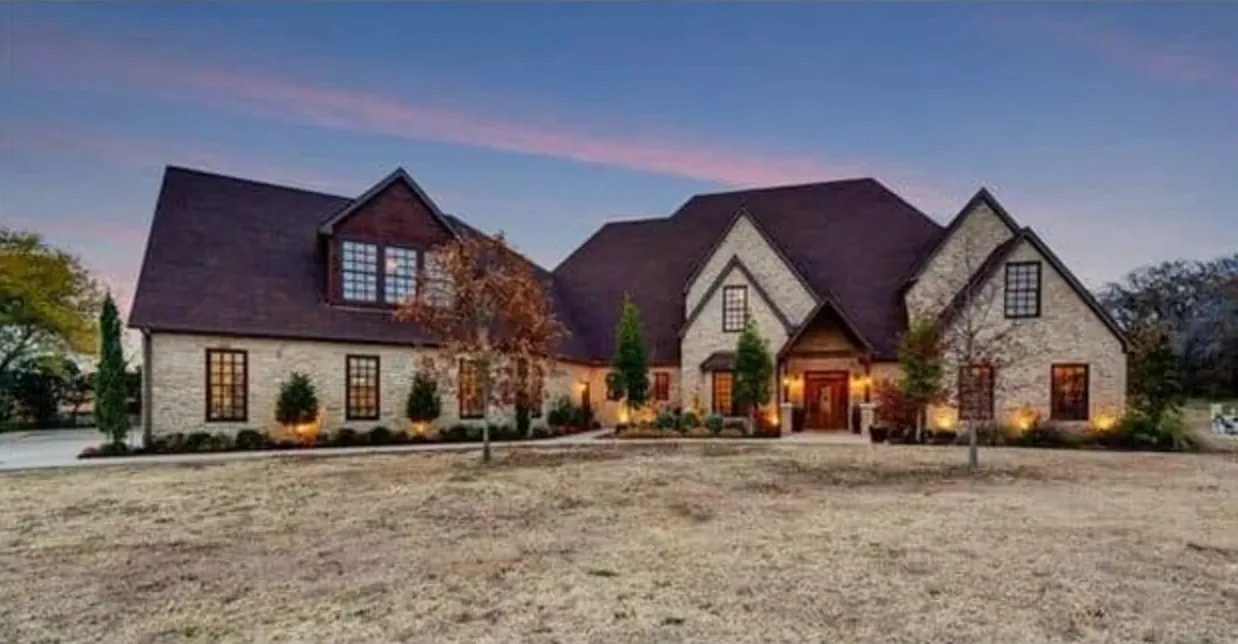 Limestone custom home with steep dark roofs at dusk