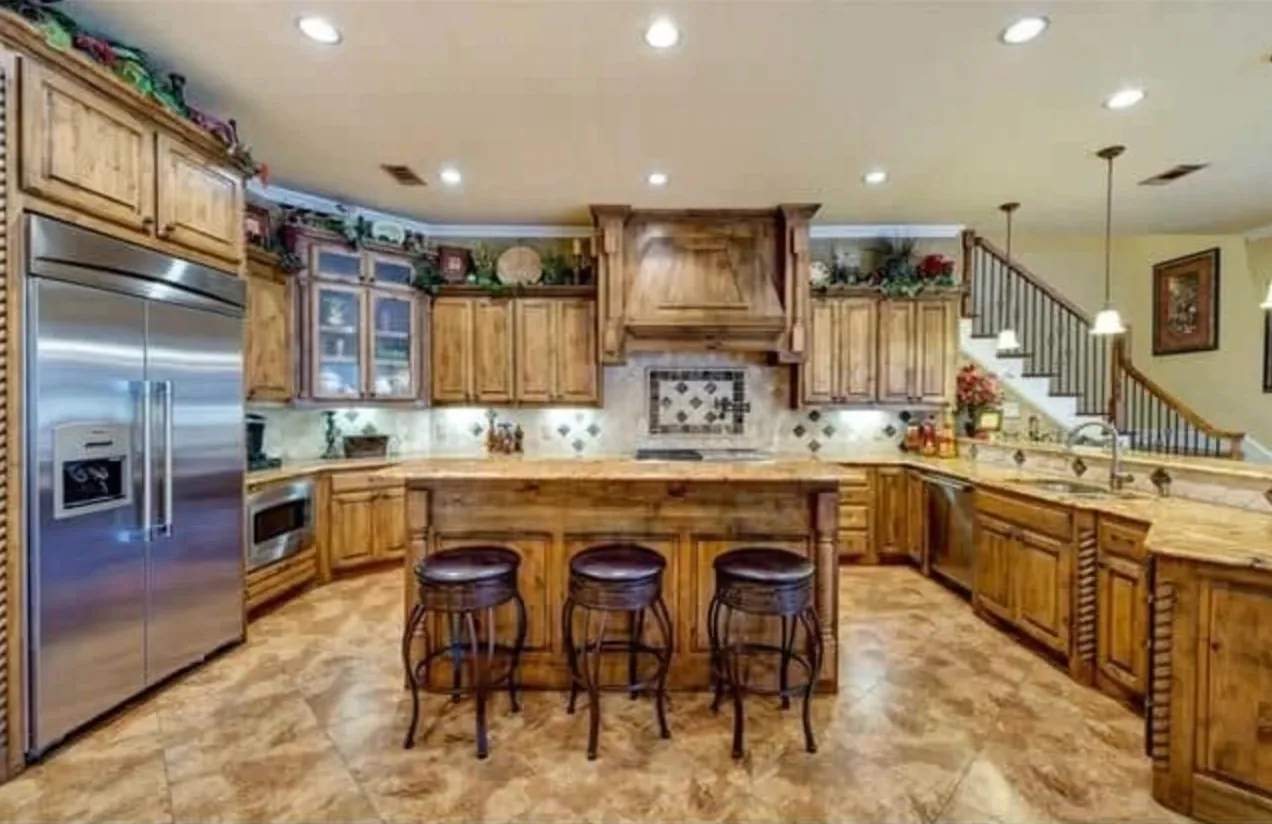 Kitchen with knotty alder cabinets, a wood range hood and a granite island