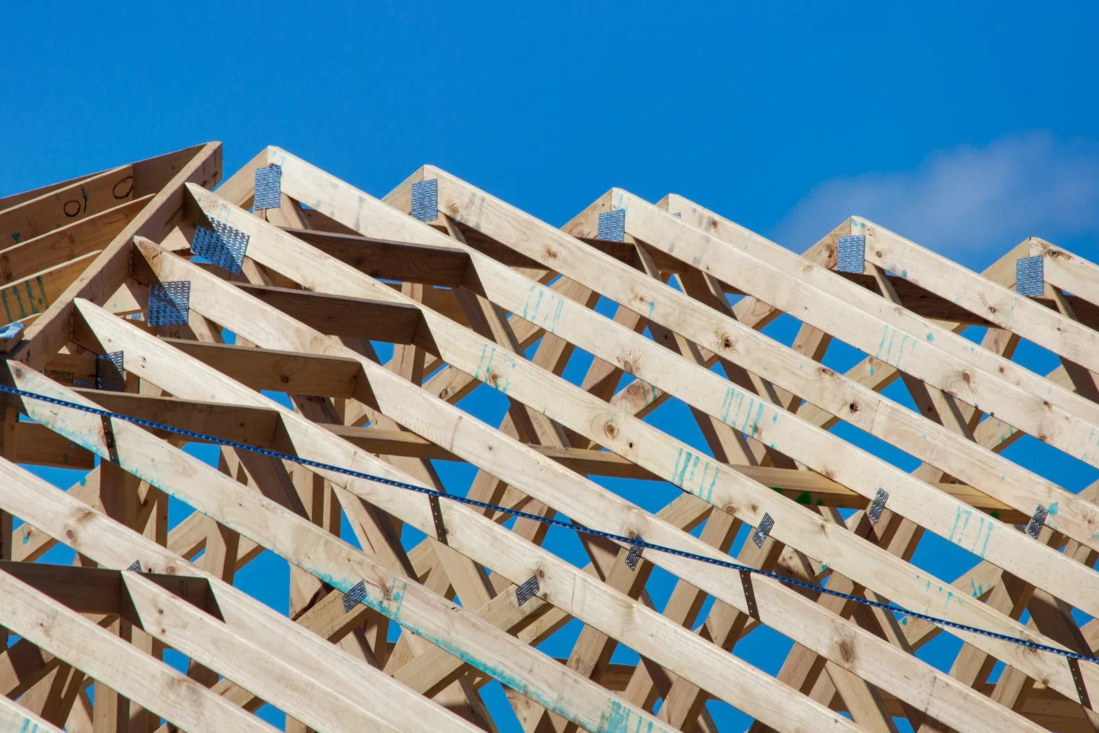 Rows of timber roof trusses against a clear blue sky