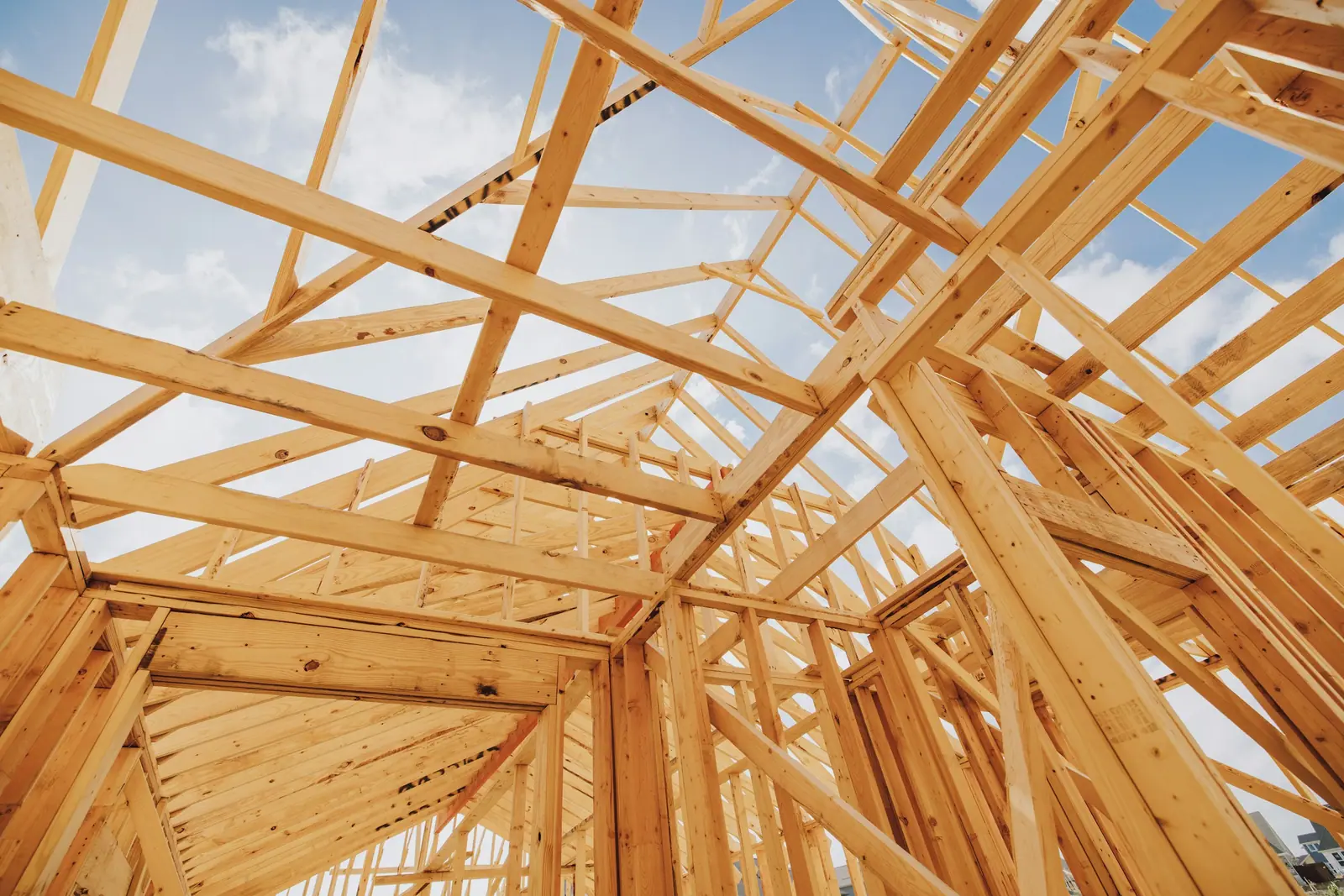 Timber wall and roof framing of a house against a blue sky